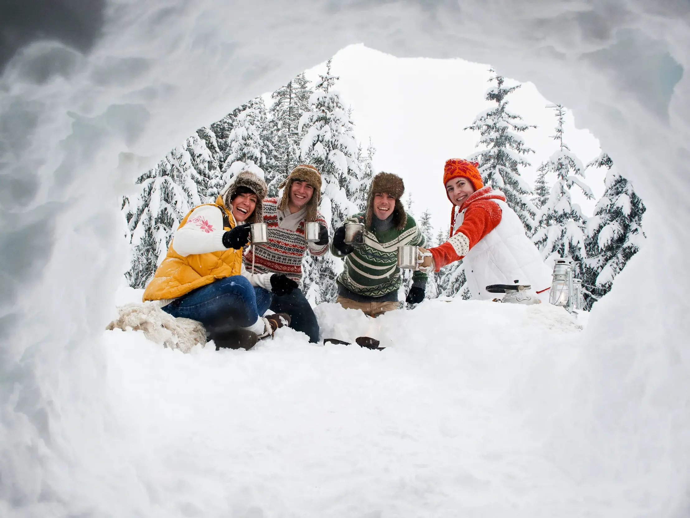 Eine fröhliche Gruppe junger Leute prostet sich mit Tassen zu, fotografiert aus einem Iglu in der verschneiten Waldlandschaft Finnlands.