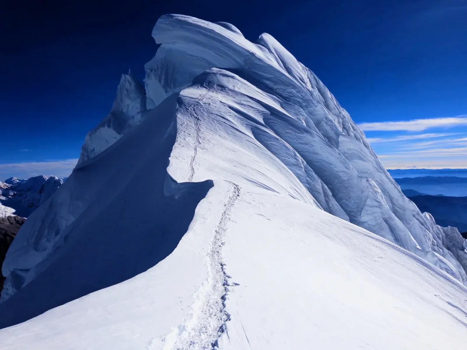 Fußspuren auf einem ausgesetzten Firngrat, der zum eisigen Gipfel des Alpamayo in der peruanischen Cordillera Blanca führt.