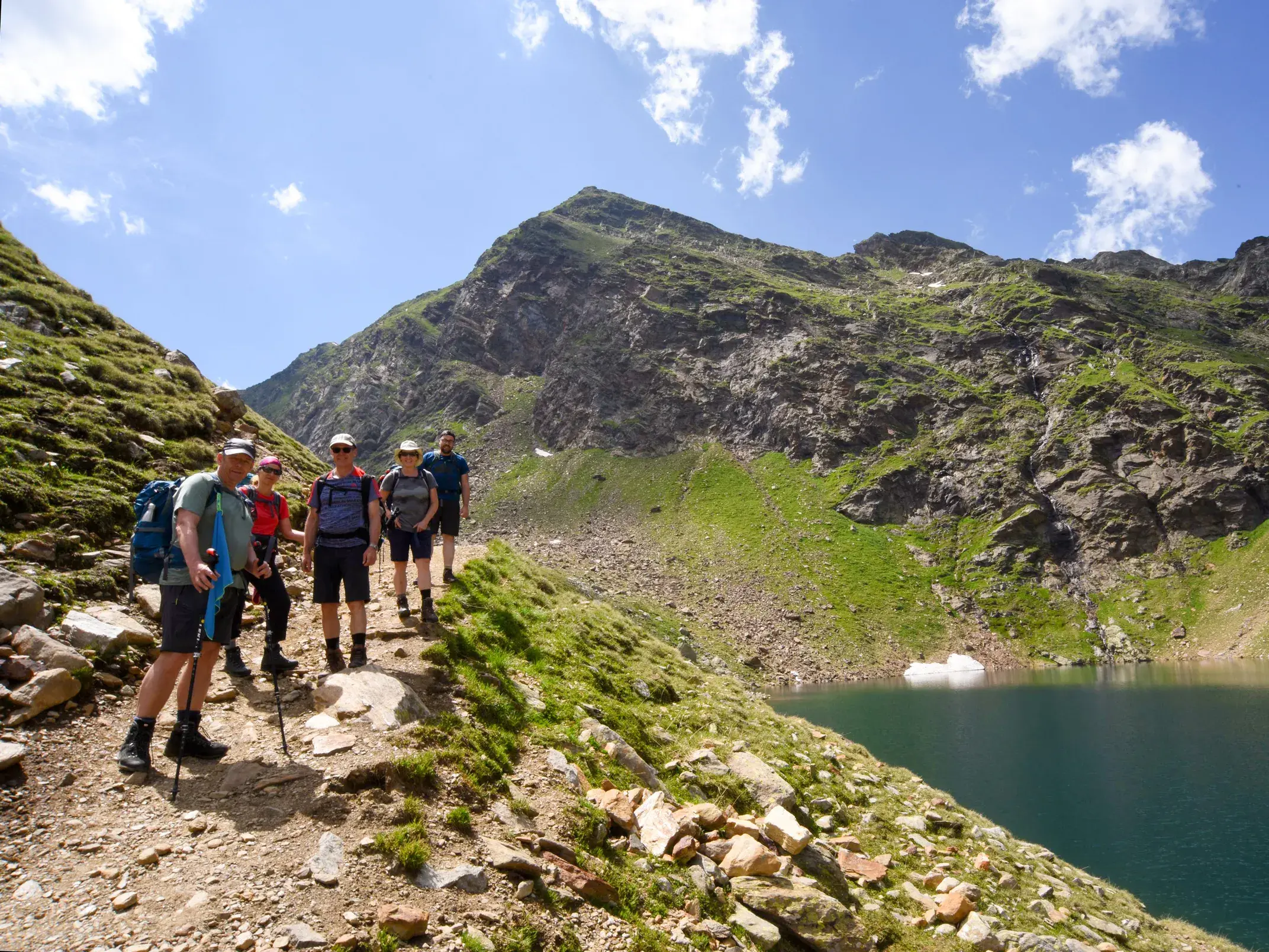 Eine Wandergruppe pausiert auf einem schmalen Pfad entlang der Spronser Seen während einer Trekkingtour in der Texelgruppe.