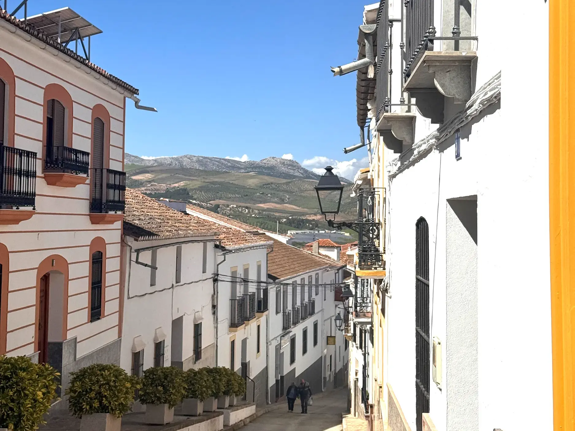 Sonnige Gasse mit weißen Häusern in der Altstadt von Antequera und Panoramablick auf die Berge des Naturschutzgebiets El Torcal.