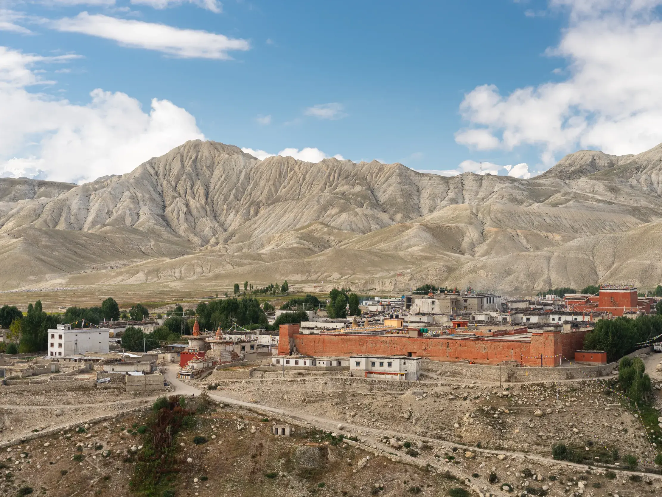 Die historische Königsstadt Lo Manthang mit ihrer roten Stadtmauer, eingebettet in die karge Berglandschaft Mustangs in Nepal.