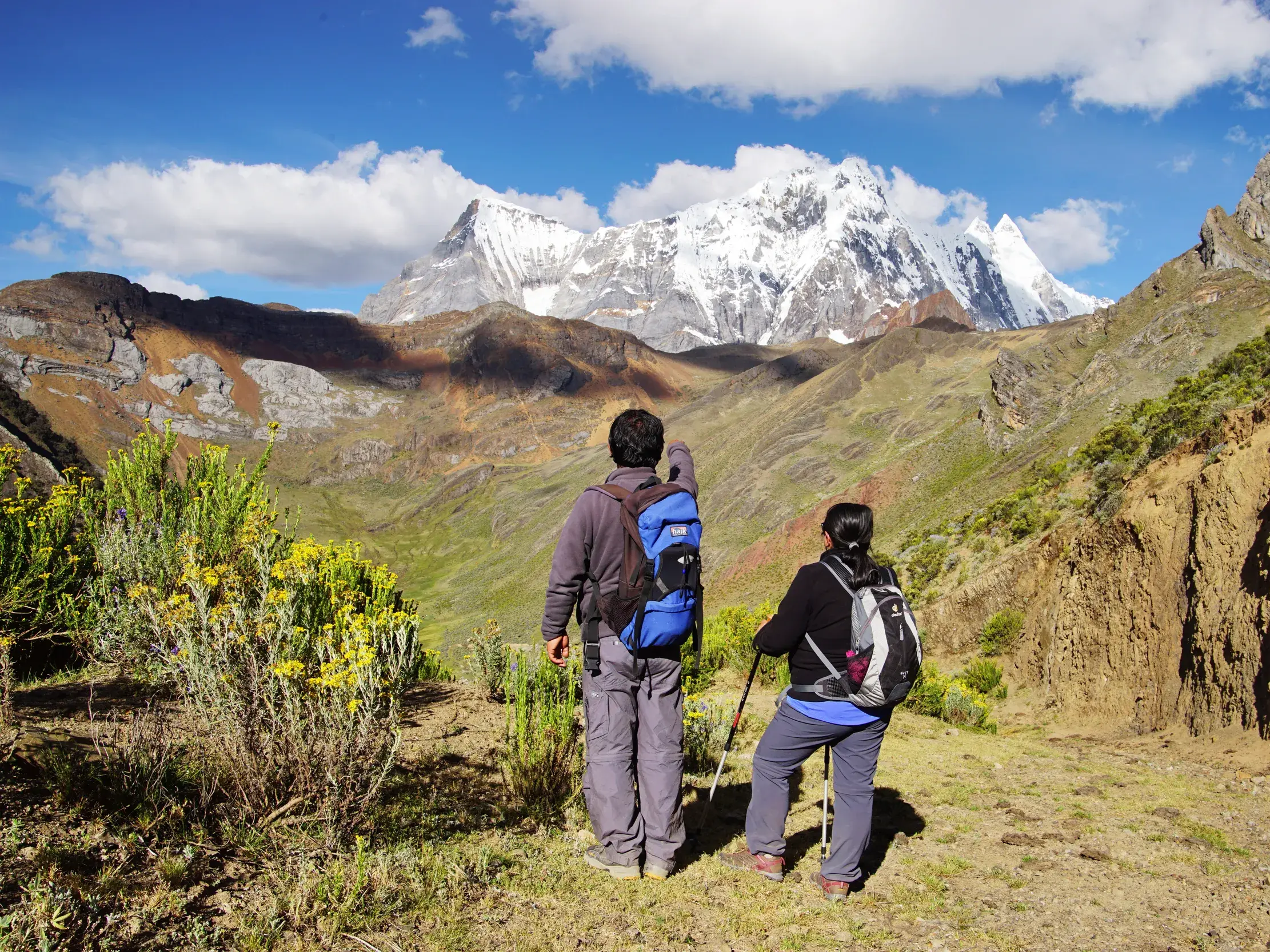 Ein Wanderer zeigt seiner Begleiterin auf einer Trekking-Tour den schneebedeckten Gipfel des Huascarán in der Cordillera Blanca.