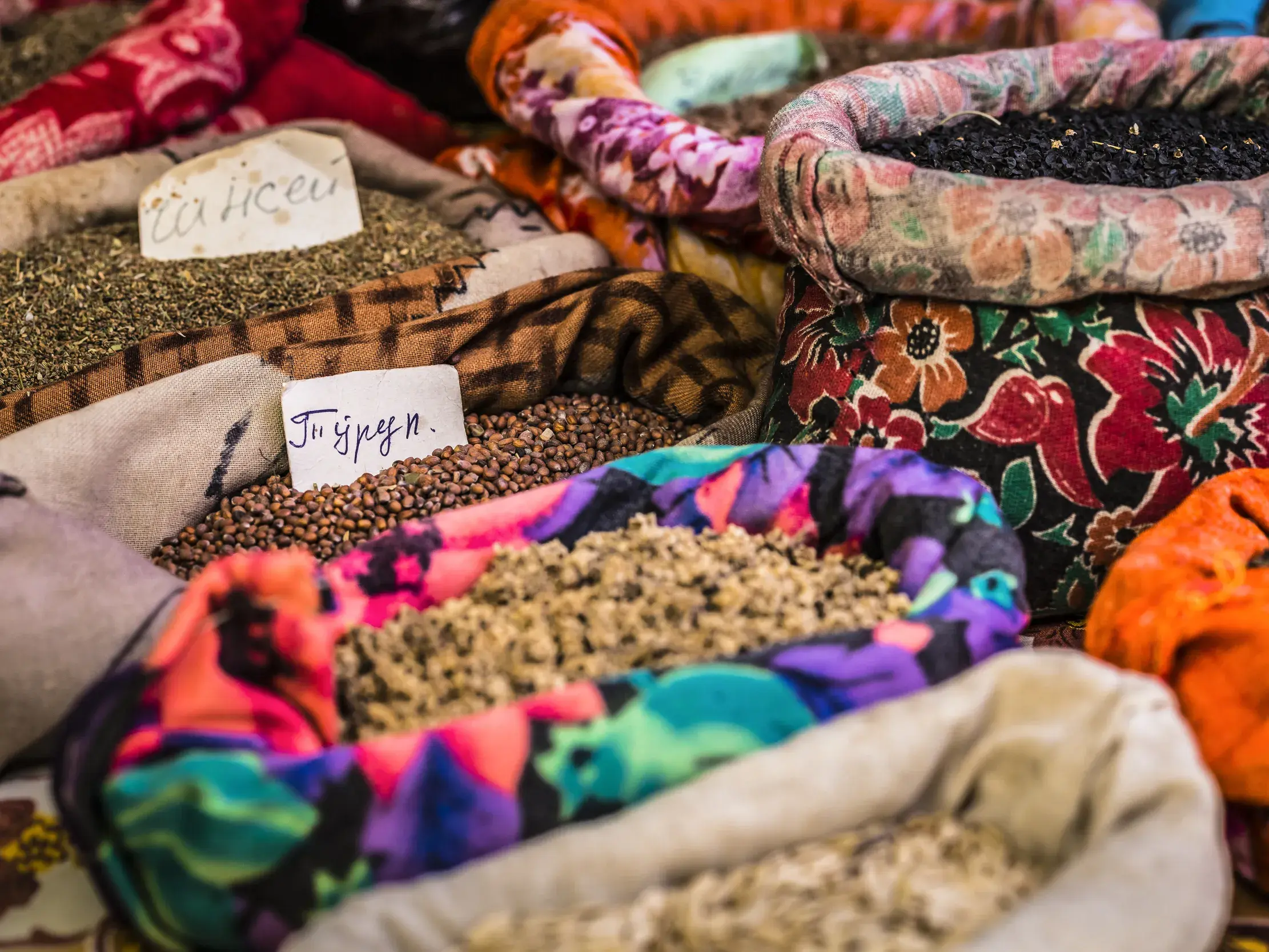Vielfalt an Getreide und Gewürzen in bunten Stoffsäcken auf einem Marktstand des Osch-Basars in Bischkek.
