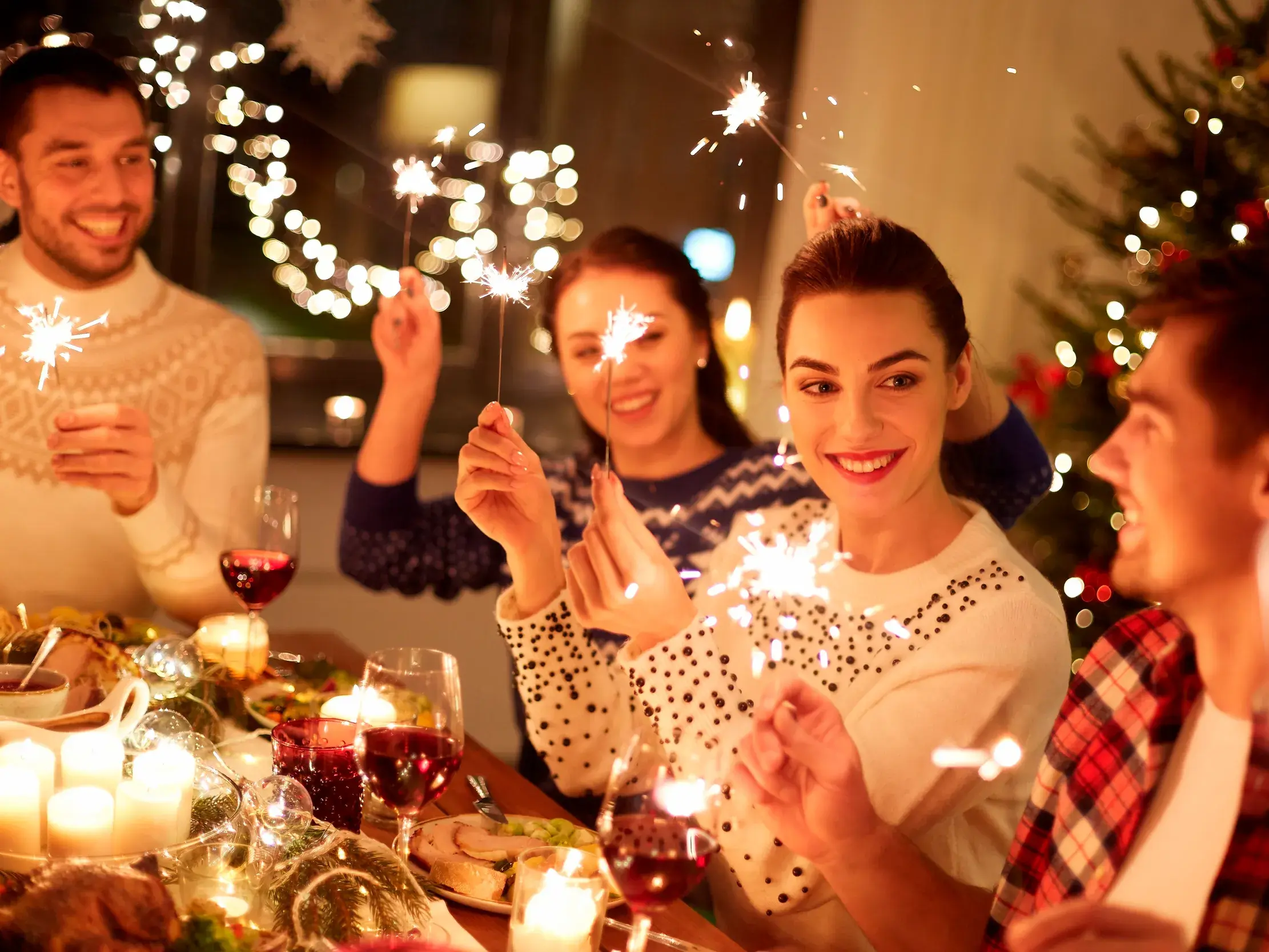 Eine Gruppe Alleinreisender feiert bei einem festlichen Silvester-Dinner gemeinsam mit Wunderkerzen das neue Jahr.