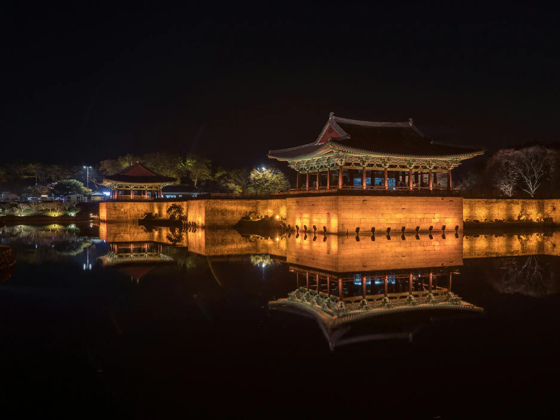 Der Donggungen-Palast in Gyeongju bei Nacht, dessen beleuchtete Pagode sich malerisch im ruhigen Wolji-Pond spiegelt.