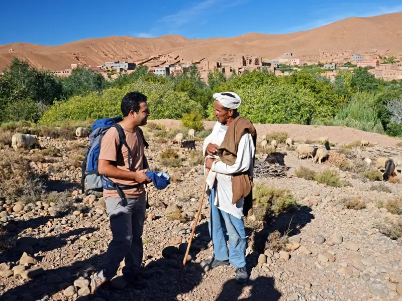 Authentische Begegnung auf einer Trekkingreise: Ein Wanderer im Gespräch mit einem Berber-Hirten im Saghro-Gebirge Marokkos.