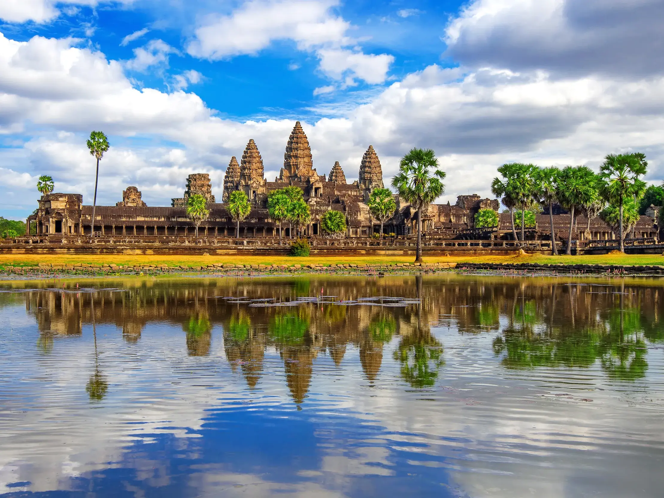 Der majestätische Tempelkomplex Angkor Wat in Kambodscha spiegelt sich an einem sonnigen Tag im ruhigen Wasser des Sees.