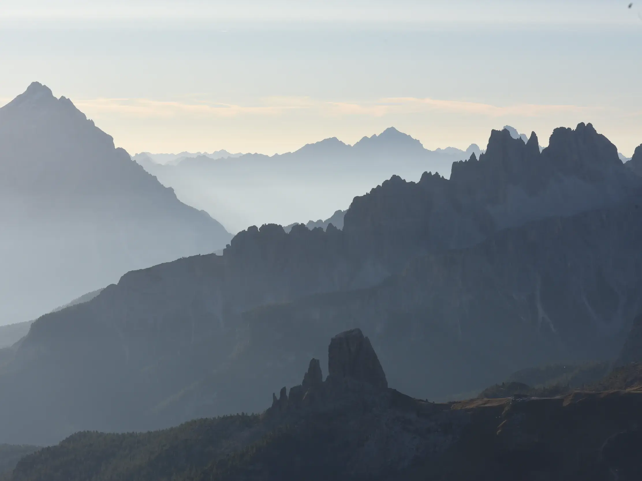 Silhouetten schroffer Berggipfel der Dolomiten ragen aus dem Nebel, eine weite Aussicht vom Höhenweg Alta Via 1.