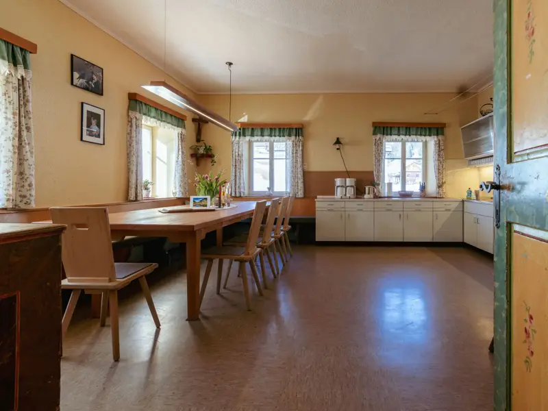 Rustikale Bauernstube im Wurzerhof: Langer Holztisch mit Eckbank und Küchenzeile im traditionellen Stil Osttirols.