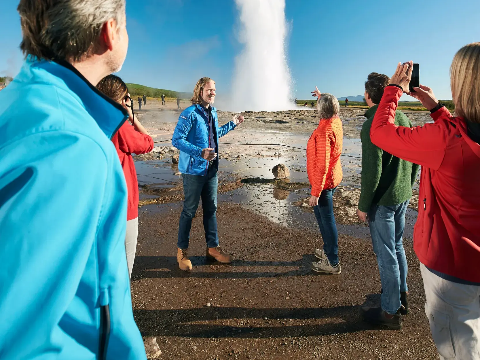 Studiosus-Reiseleiter erklärt einer Reisegruppe die Eruption des Geysirs Strokkur am Goldenen Ring in Island.