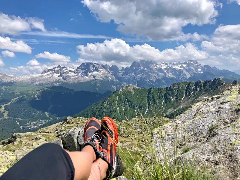Ein Wanderer macht eine Pause und genießt den Panoramablick auf die schneebedeckten, schroffen Gipfel der Brenta-Dolomiten.