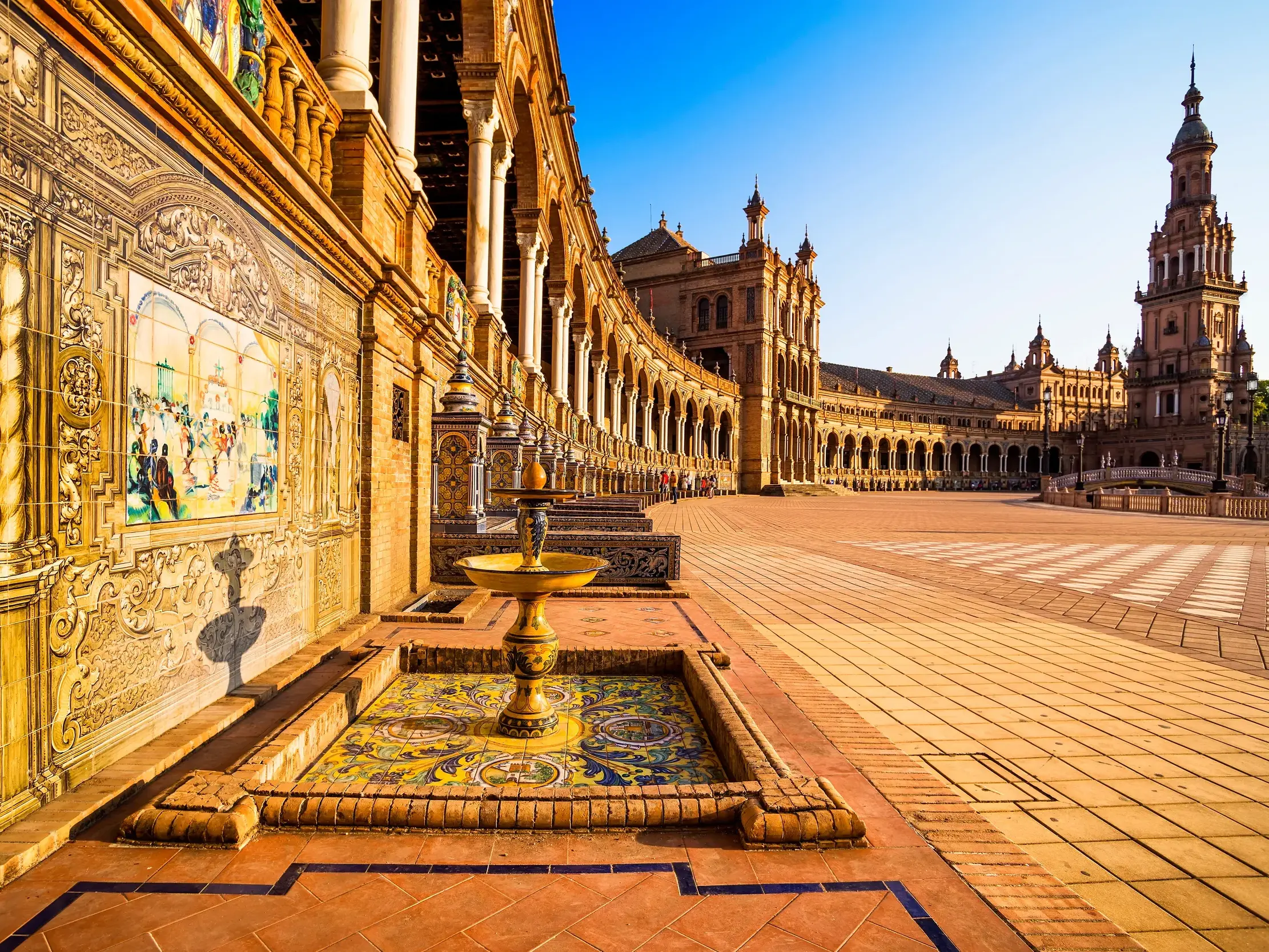 Sonniger Morgen am Plaza de España in Sevilla mit Blick auf die verzierten Arkaden, Azulejos und den Südturm.