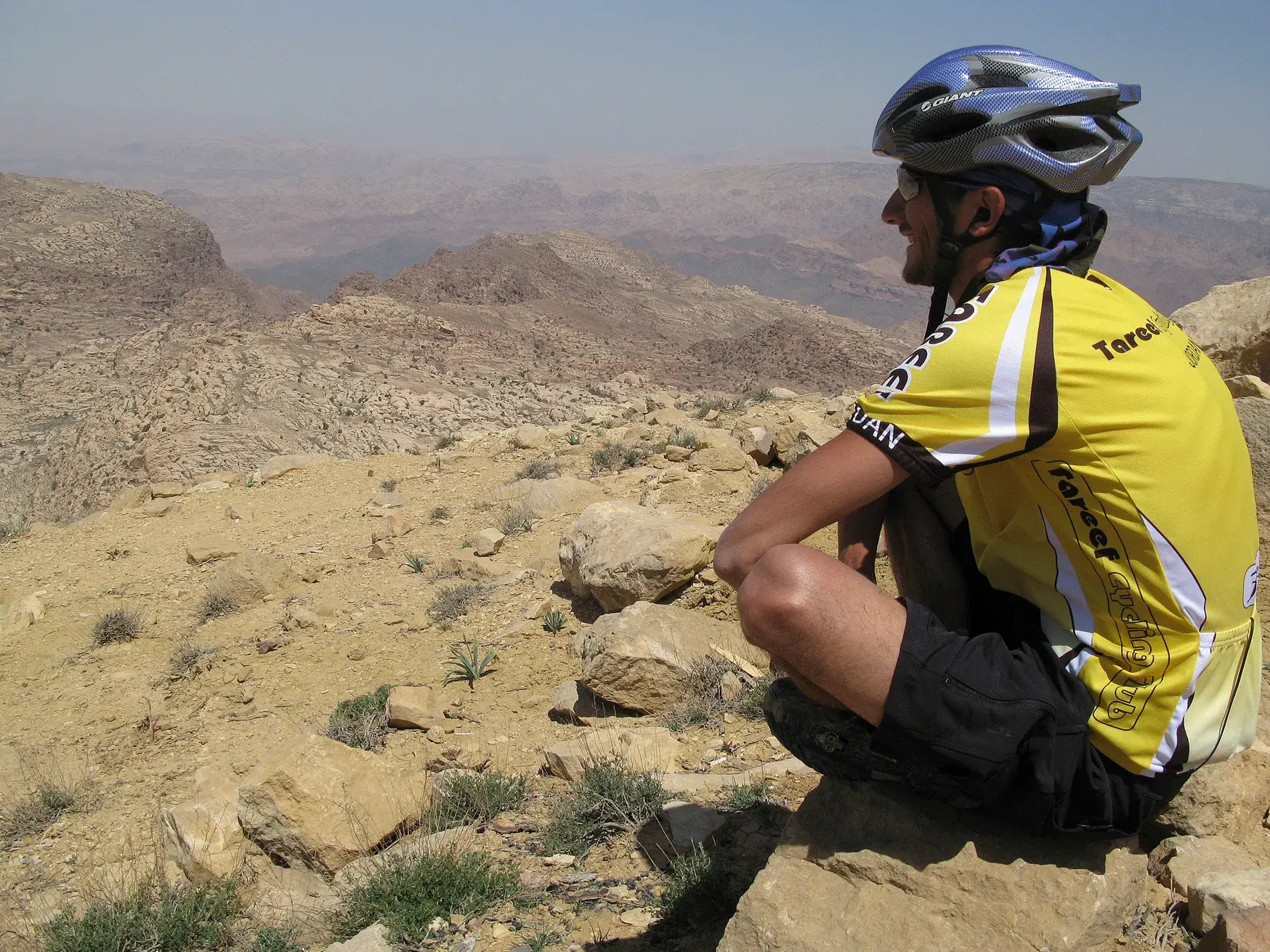 Ein Mountainbiker macht während einer geführten Rundreise in Jordanien eine Pause und genießt den Blick auf die Felslandschaft.