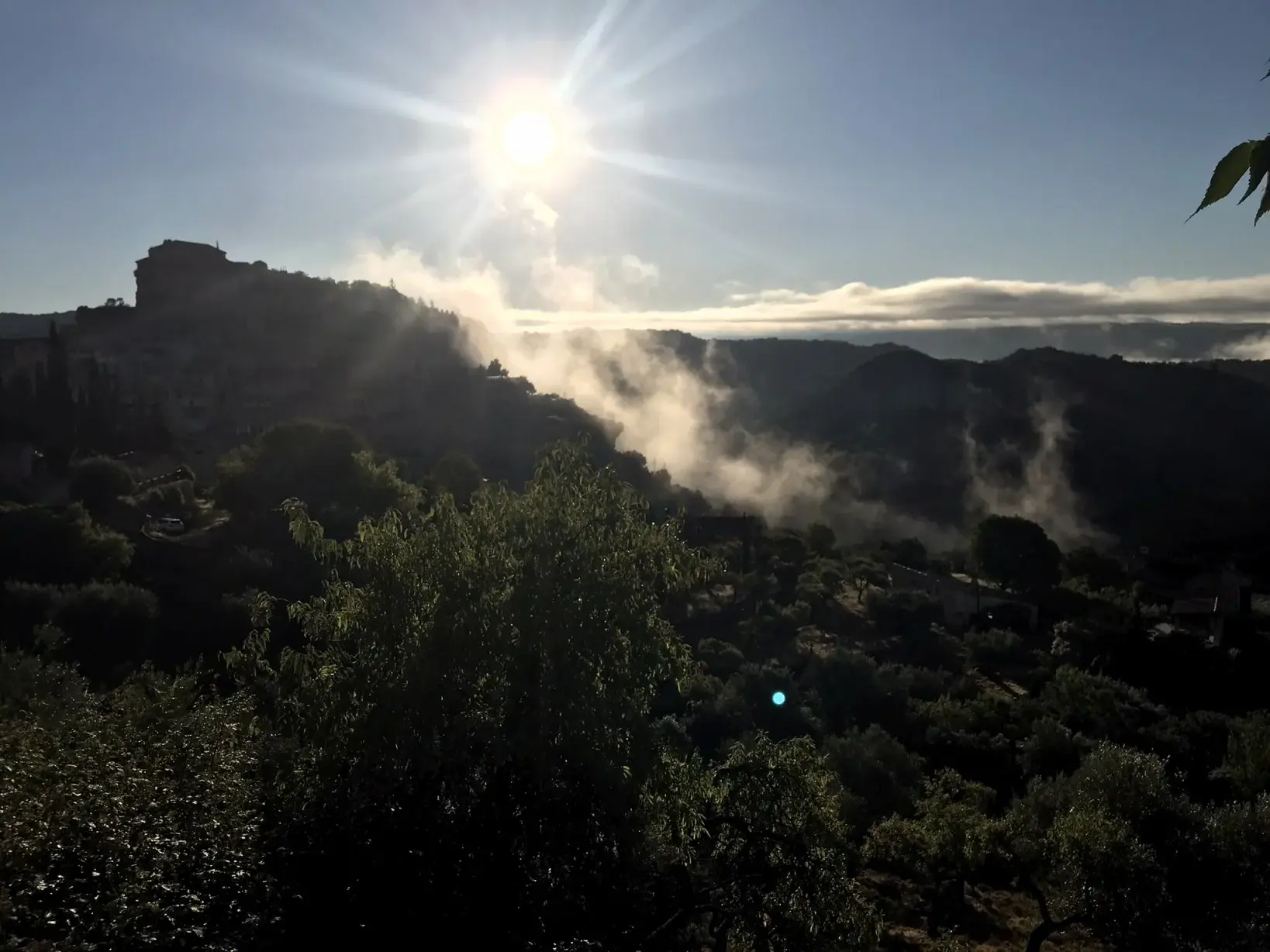 Sonnenaufgang über der Berglandschaft der Sierra de Guara mit Nebelschwaden in den Tälern und Blick auf das Dorf Alquézar.