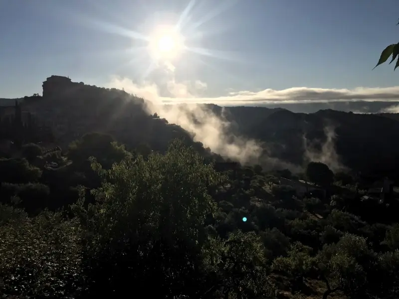 Sonnenaufgang über der Berglandschaft der Sierra de Guara mit Nebelschwaden in den Tälern und Blick auf das Dorf Alquézar.