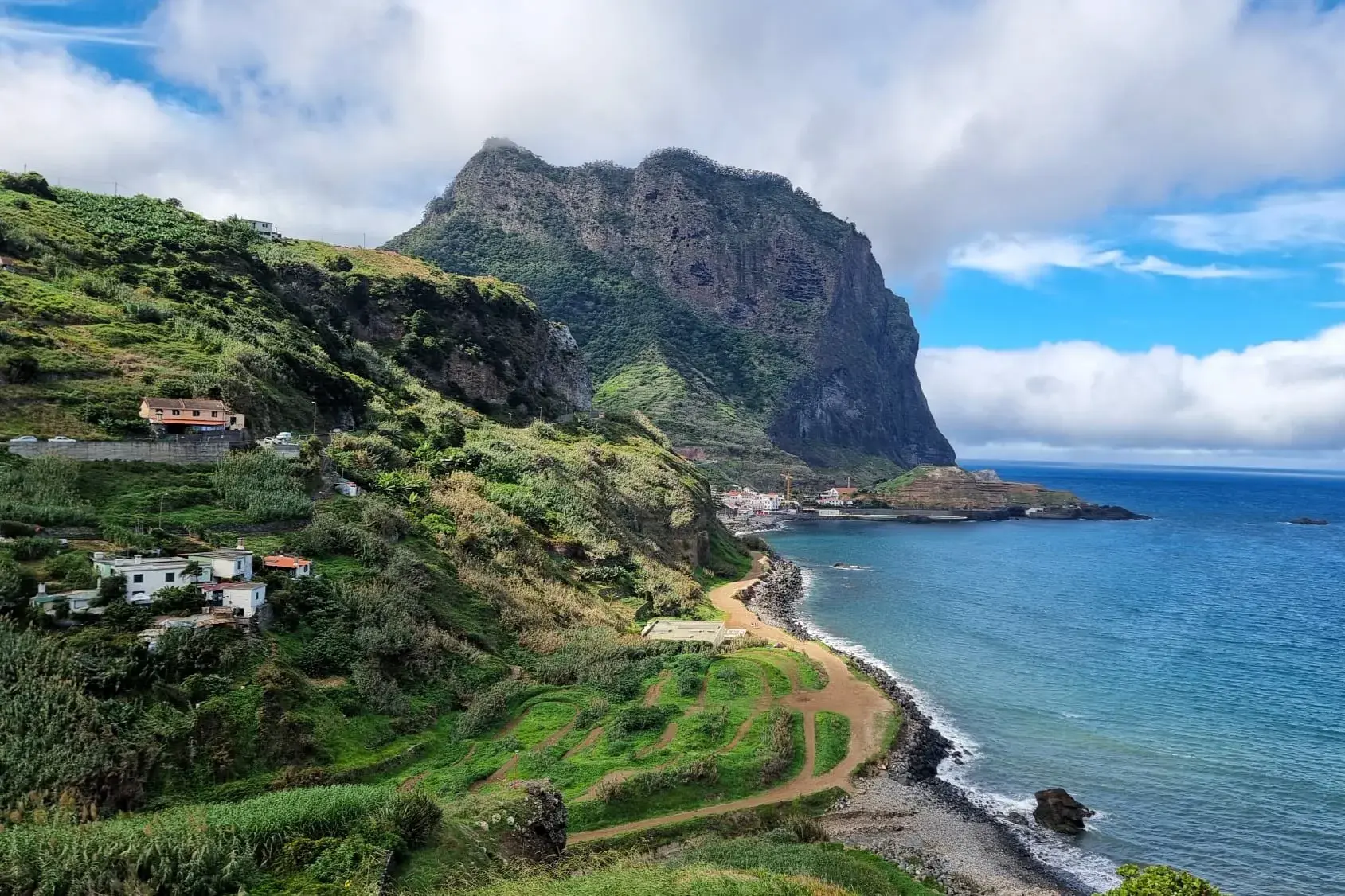 Wanderweg entlang der grünen Steilküste Madeiras mit Blick auf den imposanten Adlerfelsen und den Atlantik bei Porto da Cruz.
