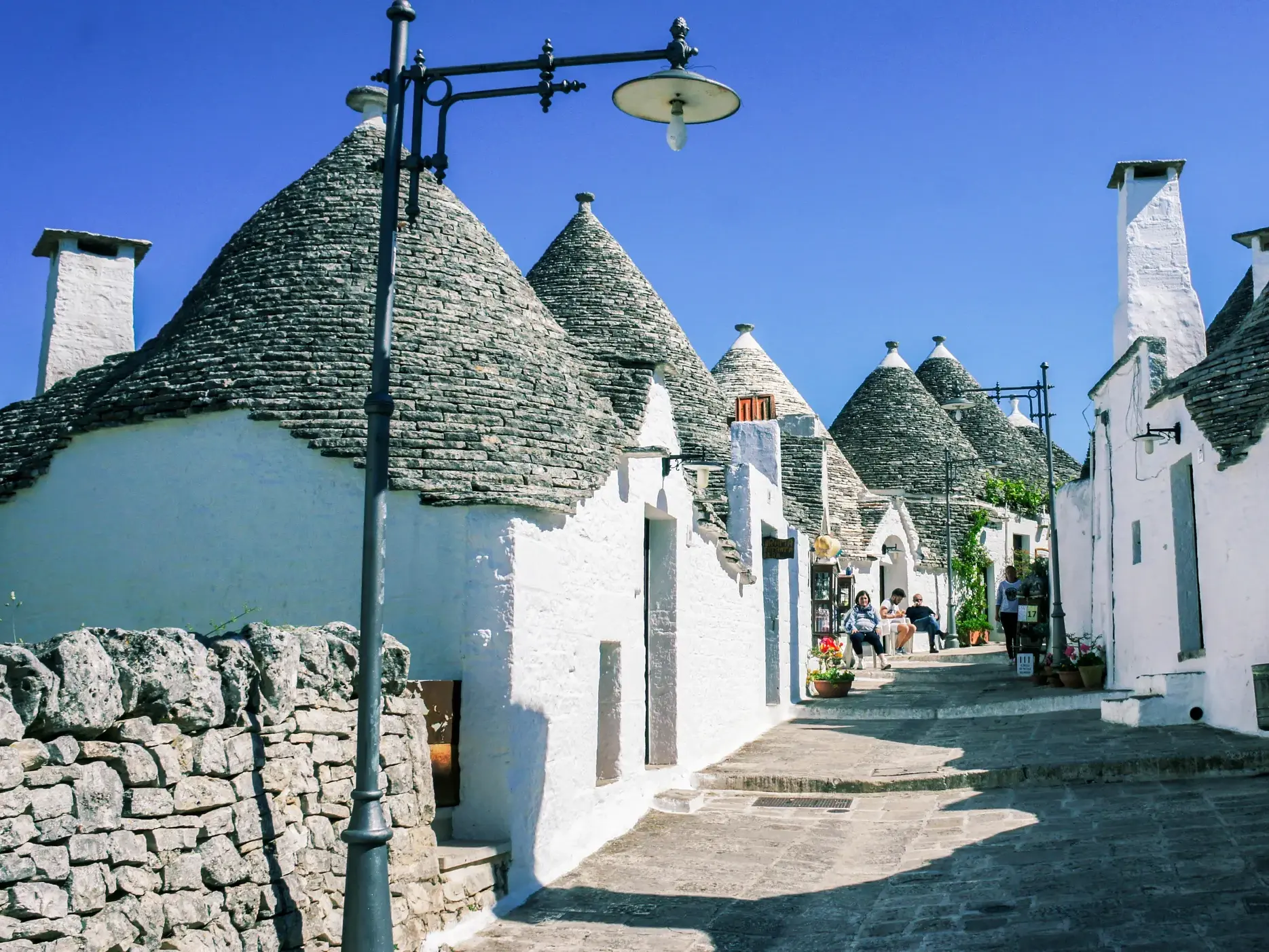 Eine enge Gasse mit weiß getünchten Trulli-Häusern und traditionellen Kegeldächern aus Stein in der Trulli-Hauptstadt Alberobello.