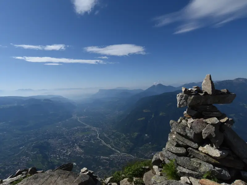 Panoramablick vom Meraner Höhenweg mit Steinmännchen im Vordergrund über das weite, sonnige Vinschgau in der Texelgruppe.