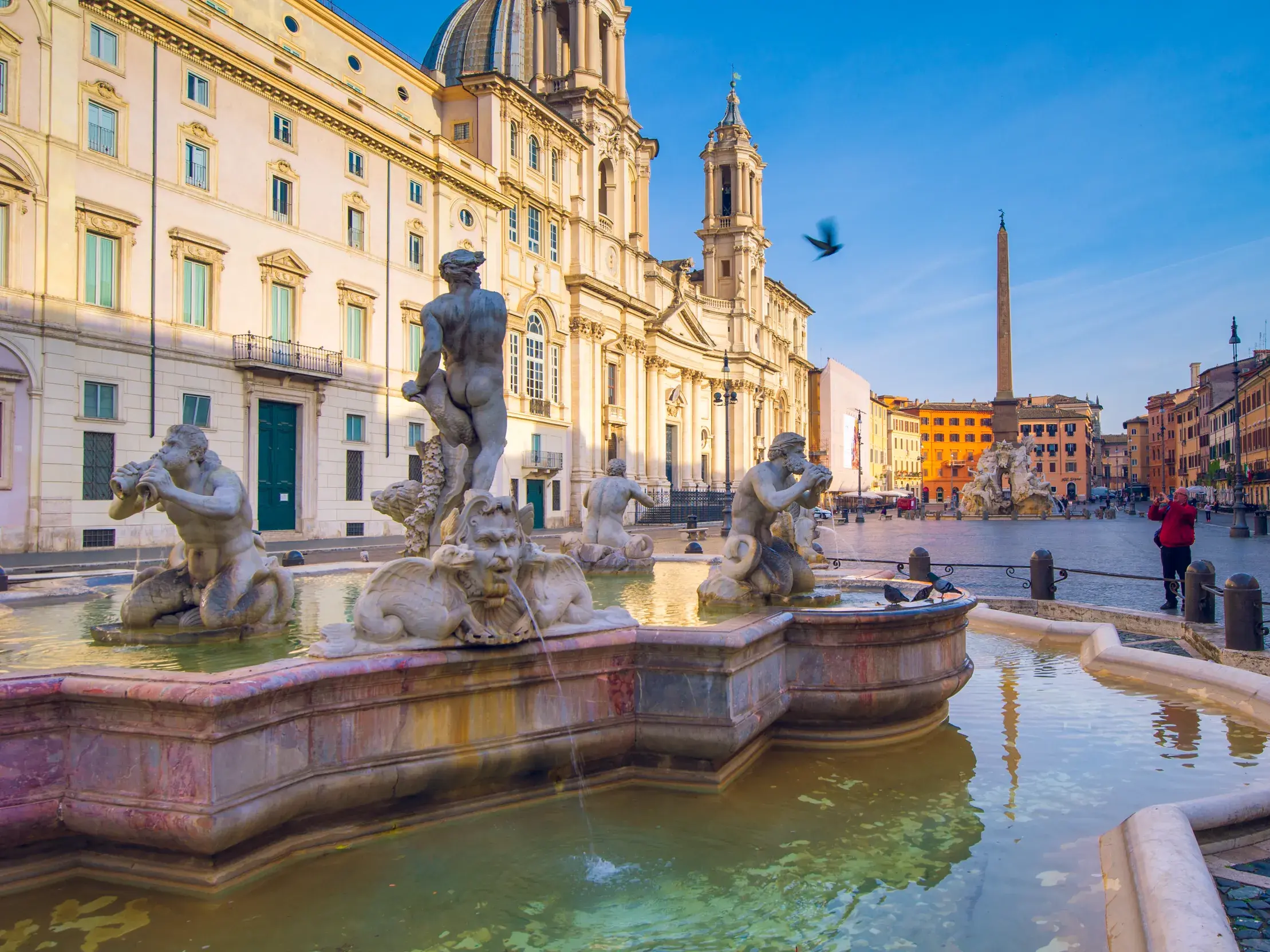 Morgenstimmung auf der Piazza Navona in Rom mit dem Moro-Brunnen im Vordergrund und Berninis Vier-Ströme-Brunnen.