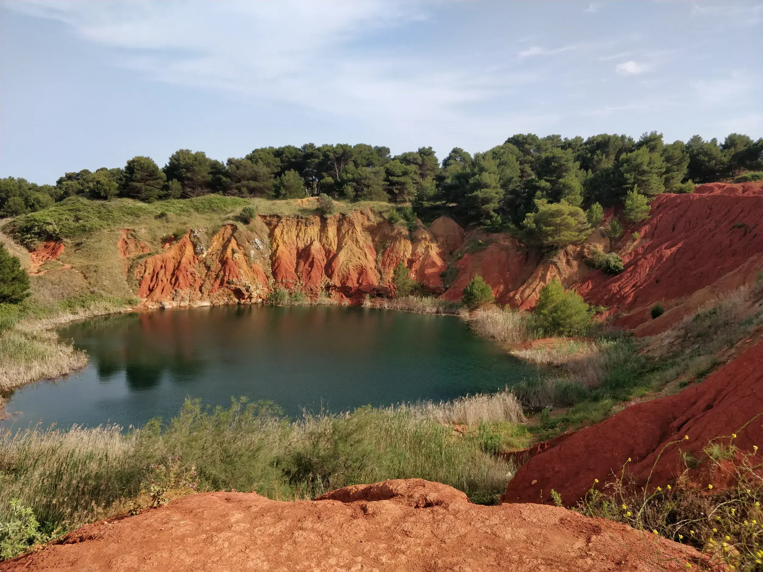 Smaragdgrüner See in der Cava di Bauxite, einem ehemaligen Steinbruch mit roter Erde bei Otranto in Apulien.