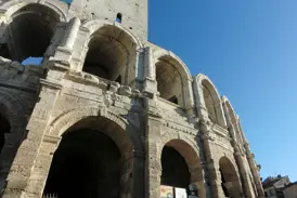 Die historischen Steinbögen der römischen Arena in Arles (UNESCO-Welterbe) unter dem strahlend blauen Himmel der Provence.