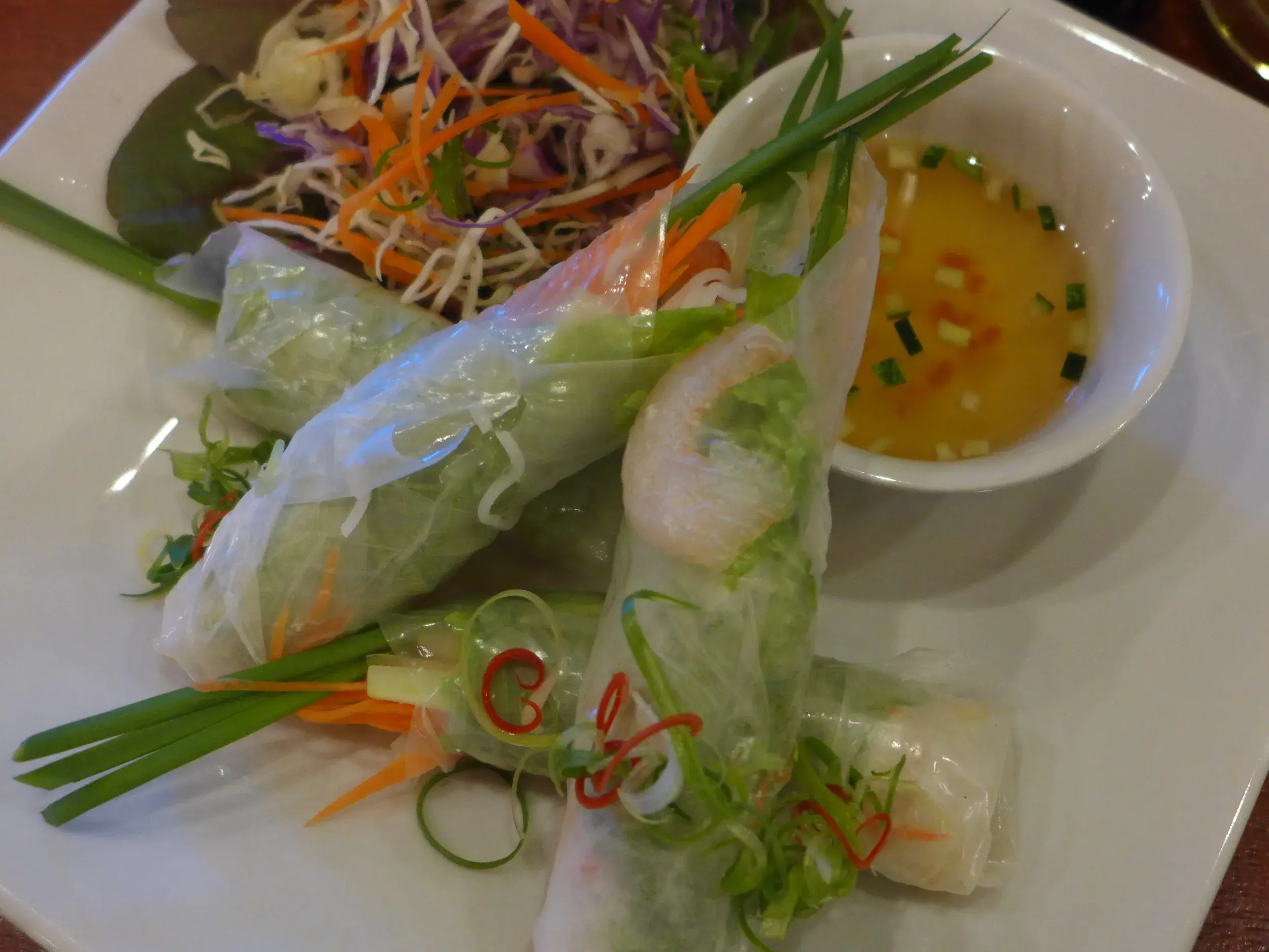 Frische vietnamesische Sommerrollen, eine kulinarische Spezialität aus Hue, mit Kräutern und Dip-Sauce auf einem Teller.