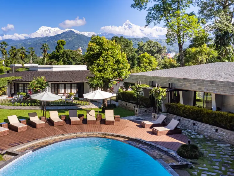 Hotelgarten der Fish Tail Lodge mit Pool und Liegen vor dem majestätischen Annapurna-Massiv in Pokhara.
