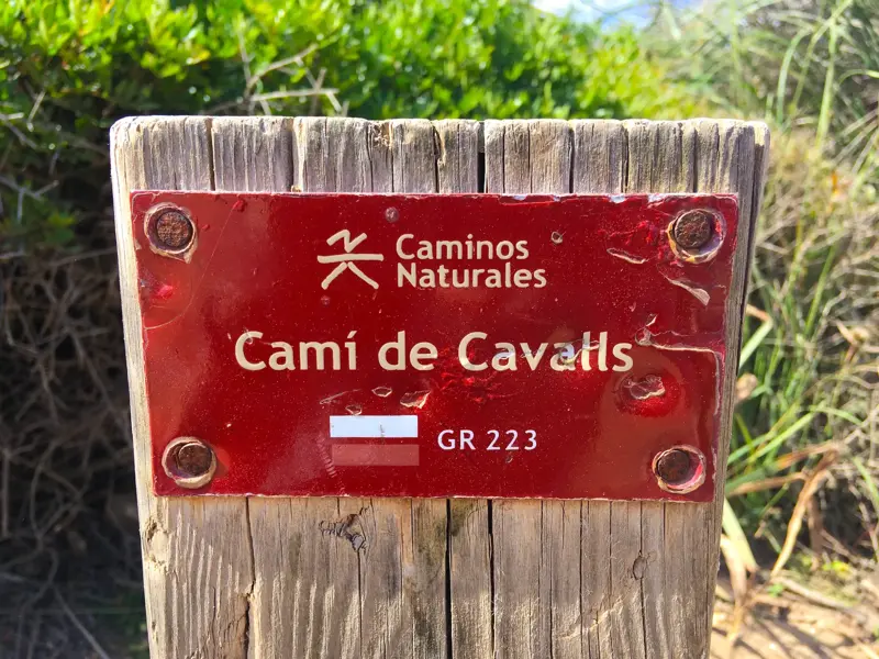 Nahaufnahme der roten Wegmarkierung des Fernwanderwegs Camí de Cavalls GR 223 auf einem Holzpfosten auf Menorca.