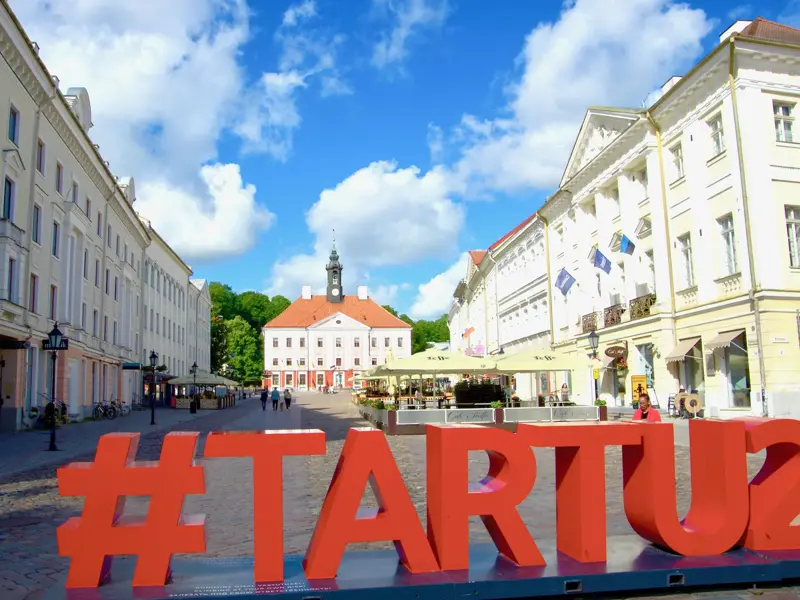 Historischer Rathausplatz in der estnischen Universitätsstadt Tartu an einem sonnigen Tag mit der #TARTU2024-Skulptur.