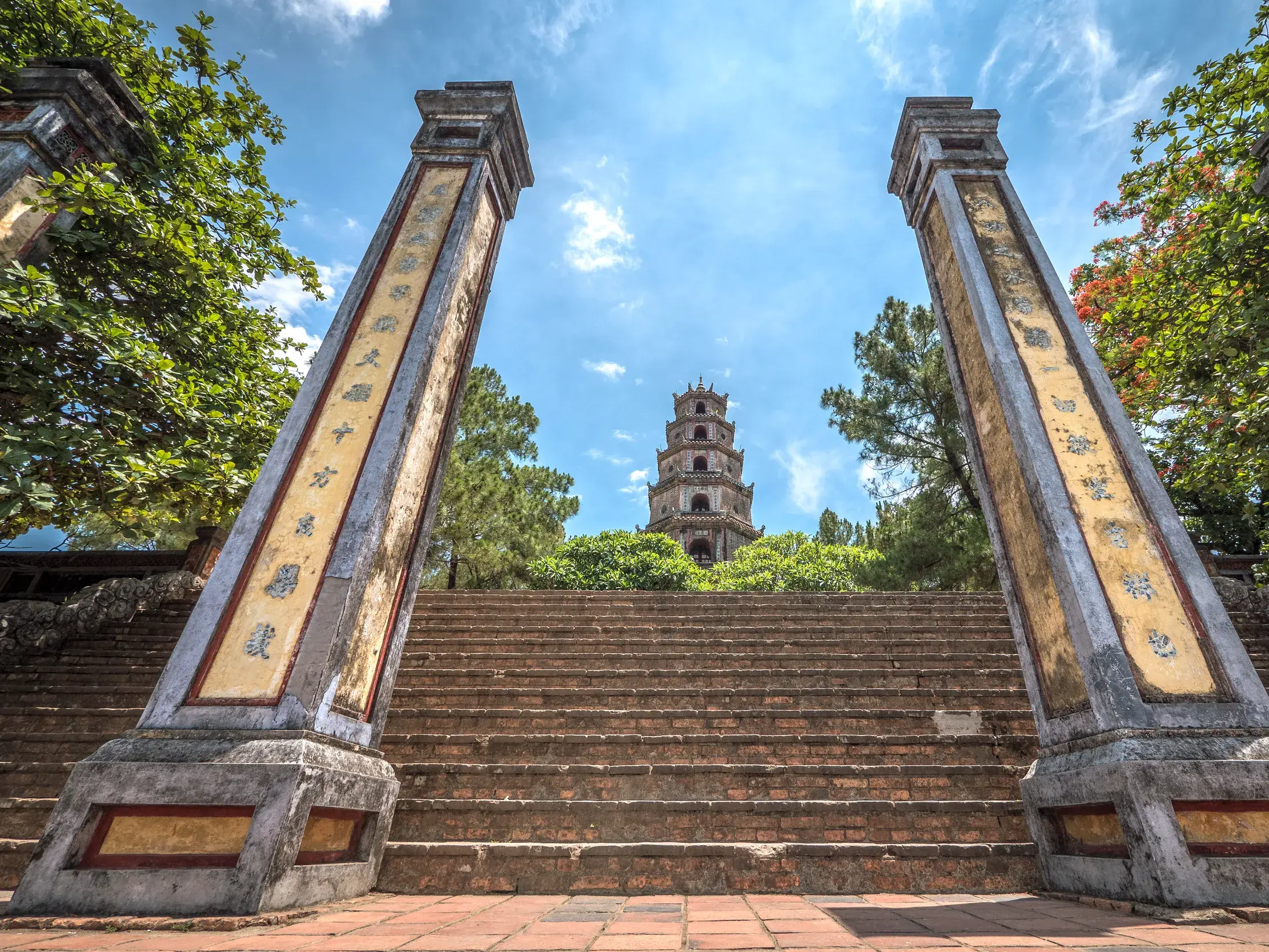 Steile Steintreppe führt hinauf zur berühmten Thien-Mu-Pagode in Hue, eingerahmt von zwei verzierten Säulen in Vietnam.