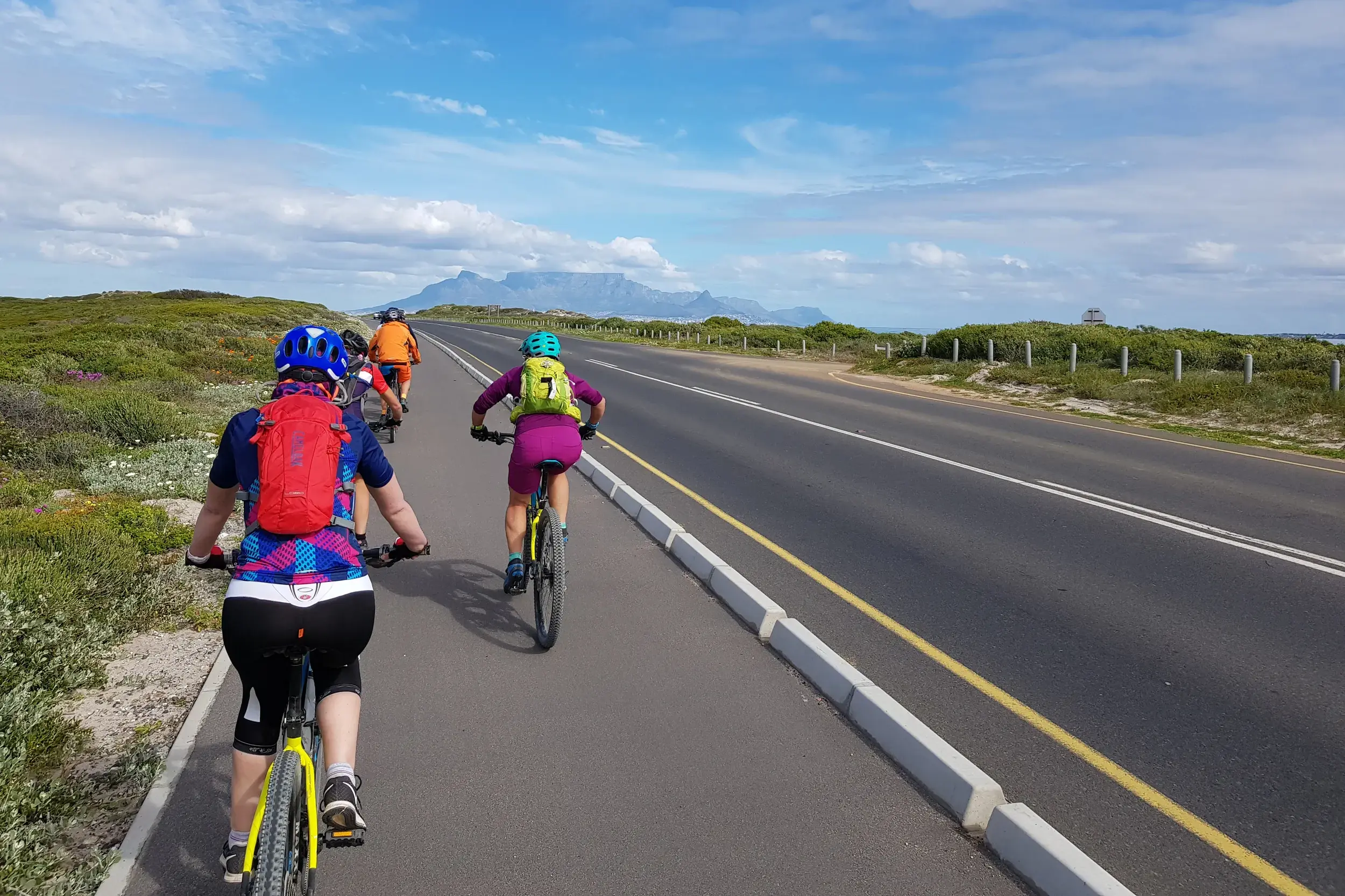 Eine Hauser Reisegruppe auf der finalen Bike-Etappe nach Kapstadt, im Hintergrund der ikonische Tafelberg in Südafrika.