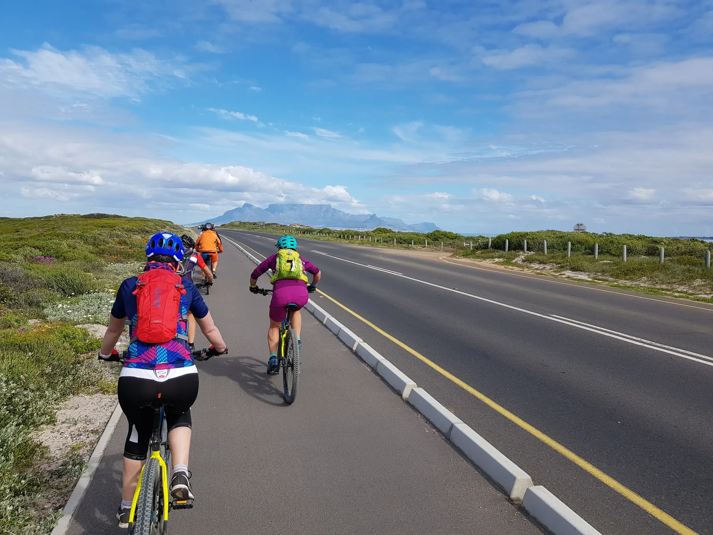 Eine Hauser Reisegruppe auf der finalen Bike-Etappe nach Kapstadt, im Hintergrund der ikonische Tafelberg in Südafrika.