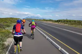 Eine Hauser Reisegruppe auf der finalen Bike-Etappe nach Kapstadt, im Hintergrund der ikonische Tafelberg in Südafrika.