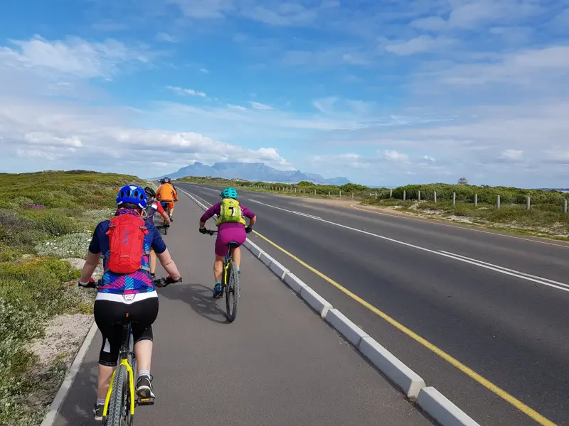 Eine Hauser Reisegruppe auf der finalen Bike-Etappe nach Kapstadt, im Hintergrund der ikonische Tafelberg in Südafrika.