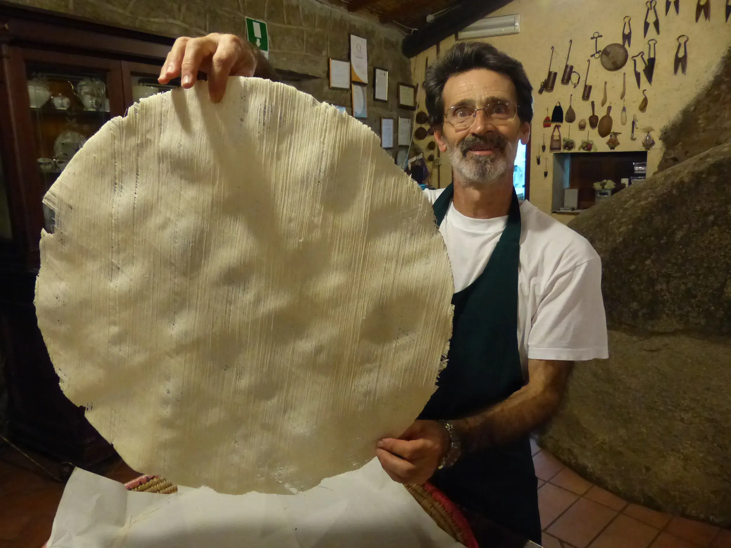 Sardischer Bauer Bastiano präsentiert stolz ein traditionelles, hauchdünnes Pane Carasau in seinem rustikalen Hof auf Sardinien.
