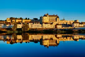 Das majestätische Schloss Amboise und die Stadt im goldenen Morgenlicht, gespiegelt in der ruhigen Loire.
