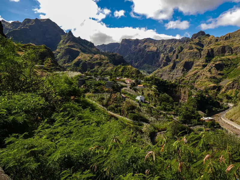 Üppig grüne Terrassenfelder und ein kleines Dorf im Paúl-Tal, eingerahmt von der schroffen Bergwelt auf Santo Antão, Kapverden.