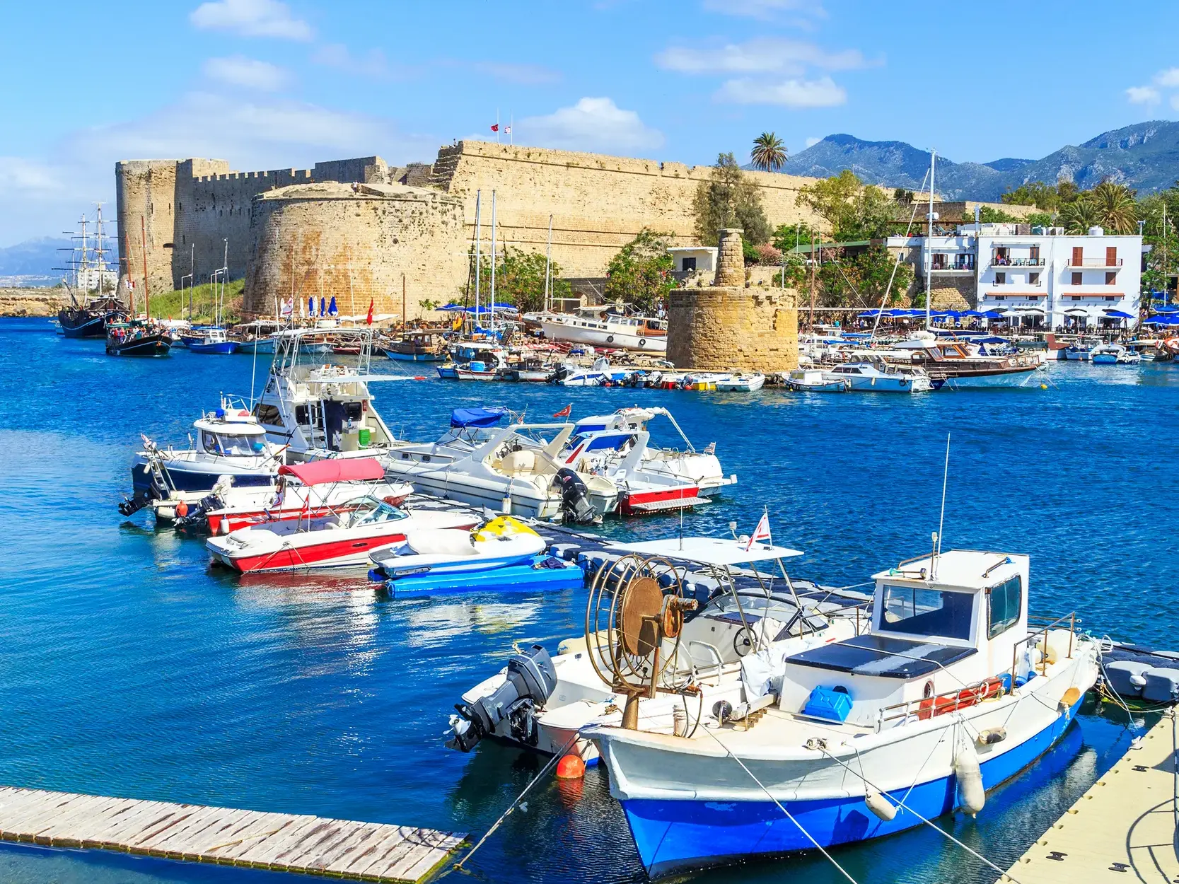 Malerischer Hafen von Kyrenia in Nordzypern mit vielen Booten im blauen Wasser vor der imposanten mittelalterlichen Festung.