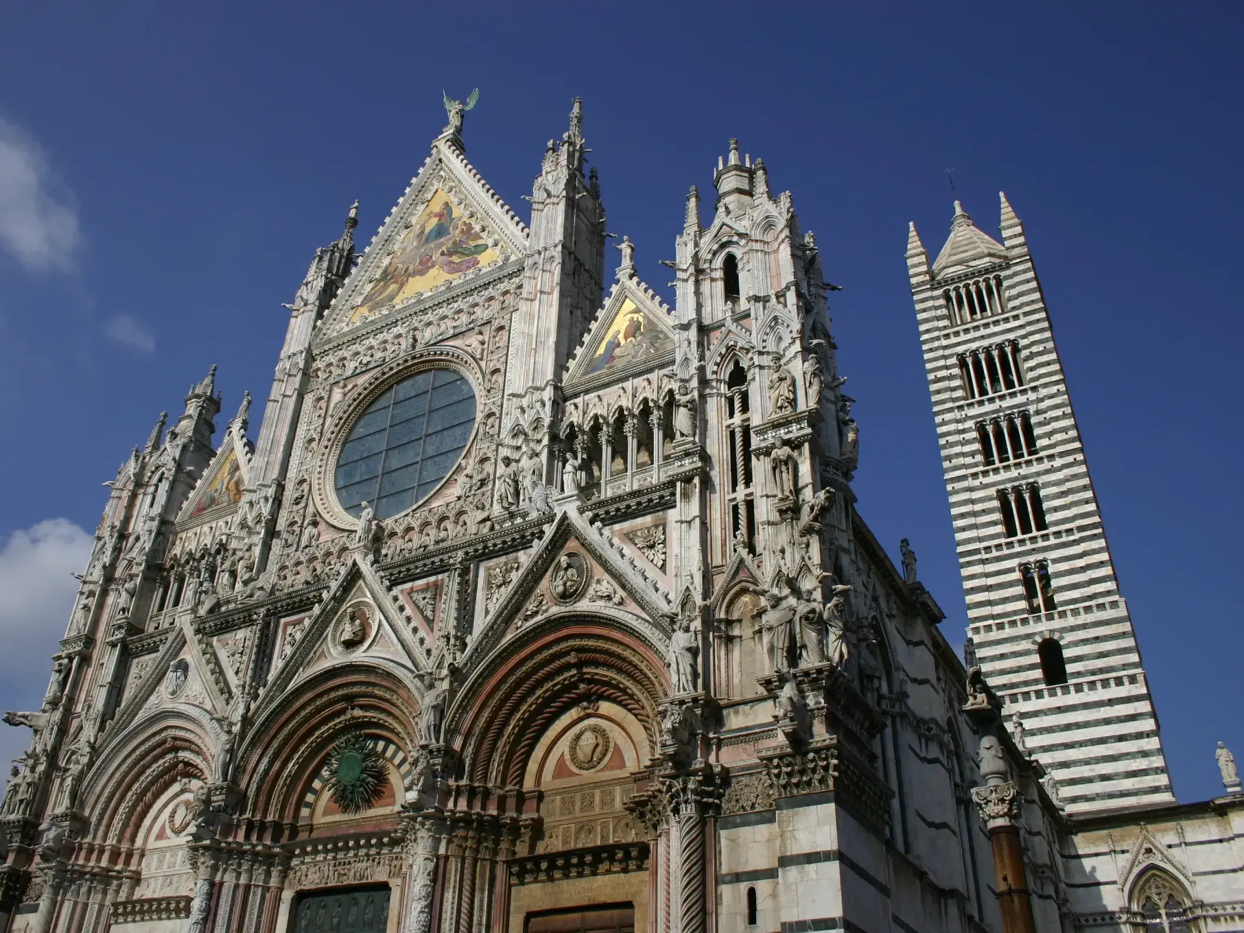 Ankunft in Siena: Die detailreiche Fassade des Doms von Siena und der Campanile, Zielpunkt der Trekkingreise in der Toskana.