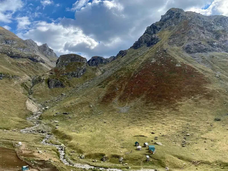 Trekking in Albanien: Einfache Holzhütten der Schäfer auf der Grama-Alm, eingebettet in die weite Berglandschaft des Korab-Gebirges.