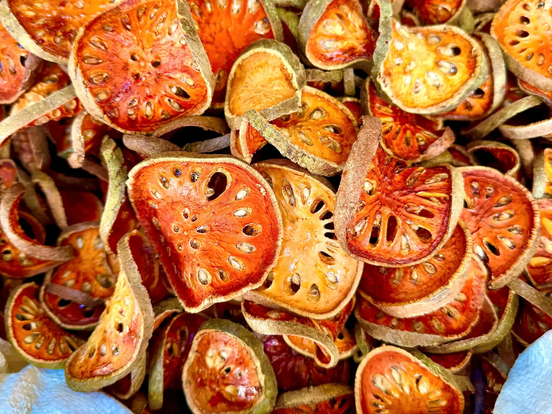Getrocknete, orangefarbene Scheiben der bengalischen Quitte (Bael-Frucht) werden auf einem Markt in Thailand angeboten.