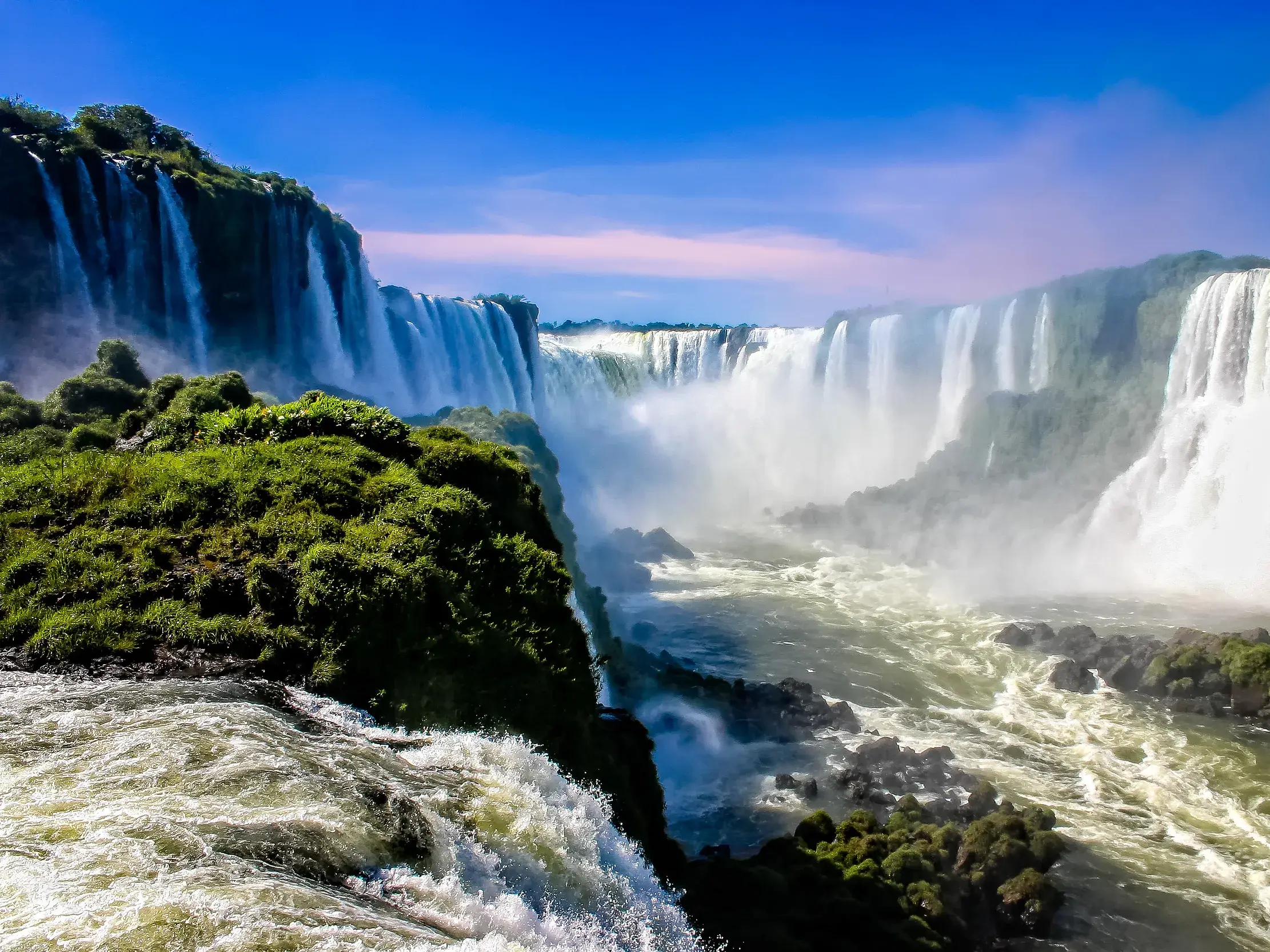 Einzigartiger Ausblick auf die tosenden Wassermassen der Iguaçu-Wasserfälle, die in eine grüne Schlucht in Brasilien stürzen.