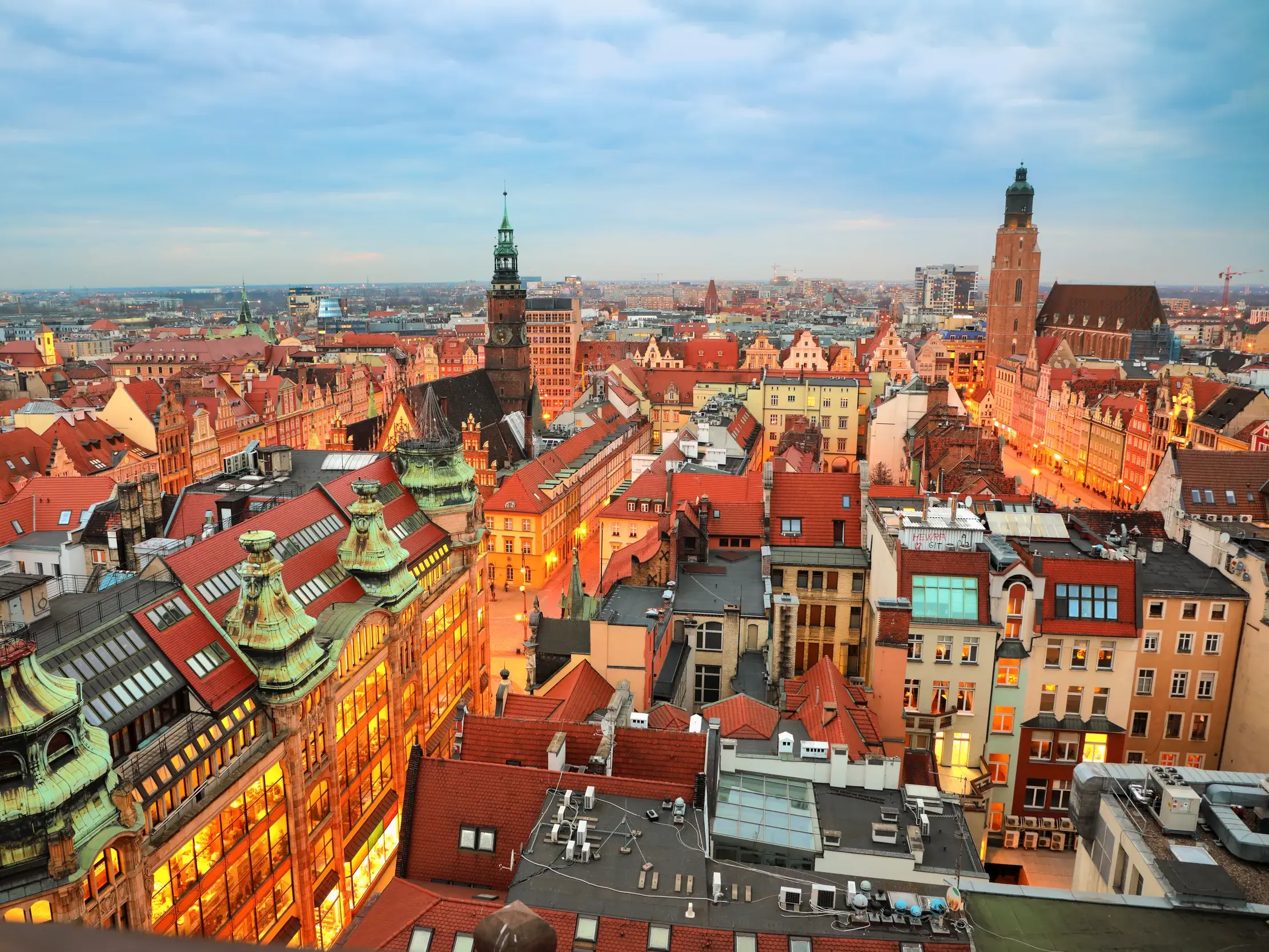 Abendlicher Panoramablick über die roten Dächer der historischen Altstadt von Breslau mit dem beleuchteten Haupt- und Salzring.
