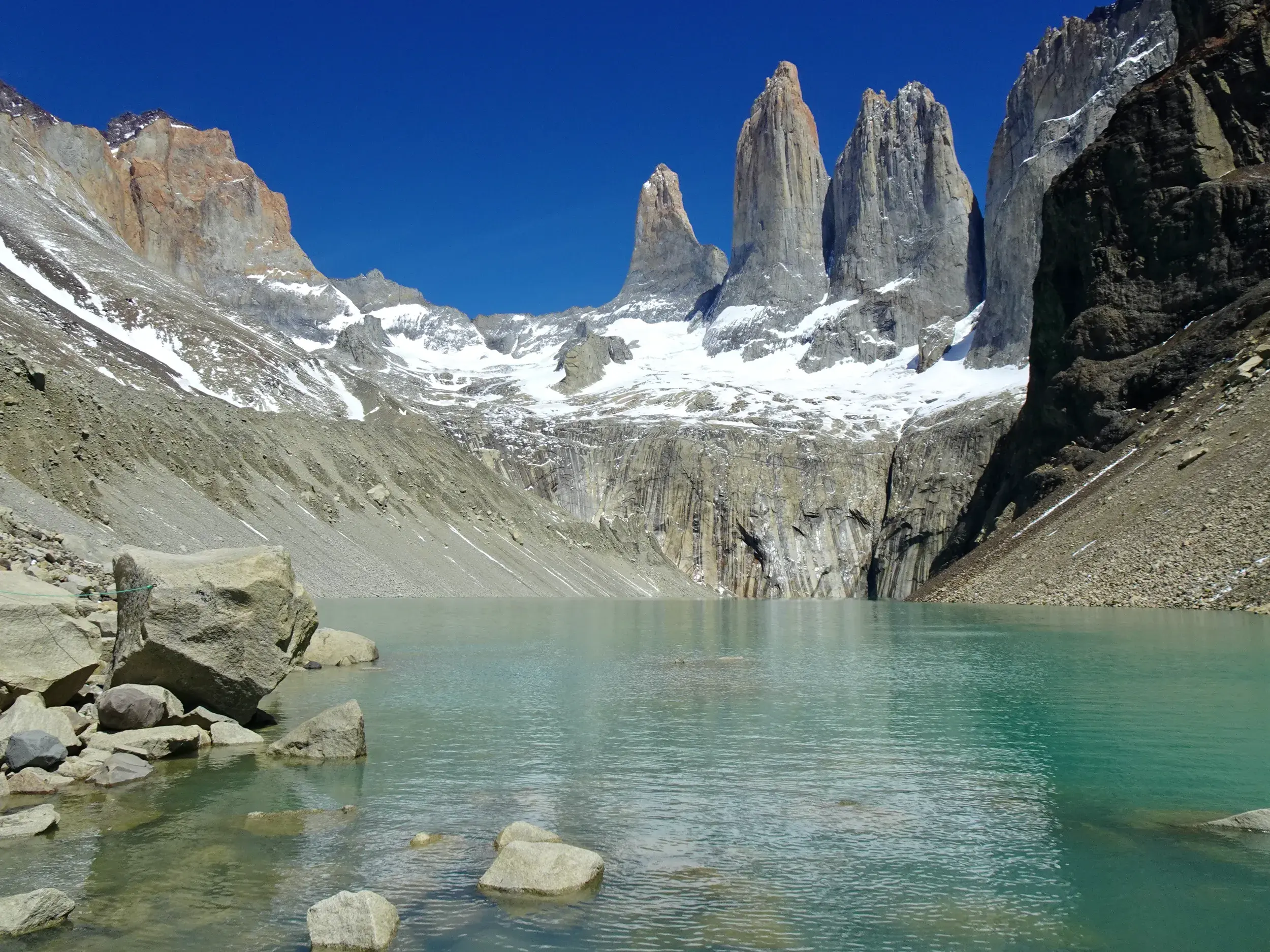 Die Felsnadeln der Torres del Paine ragen im Nationalpark in Chile über einem milchig-türkisen Gletschersee in den Himmel.