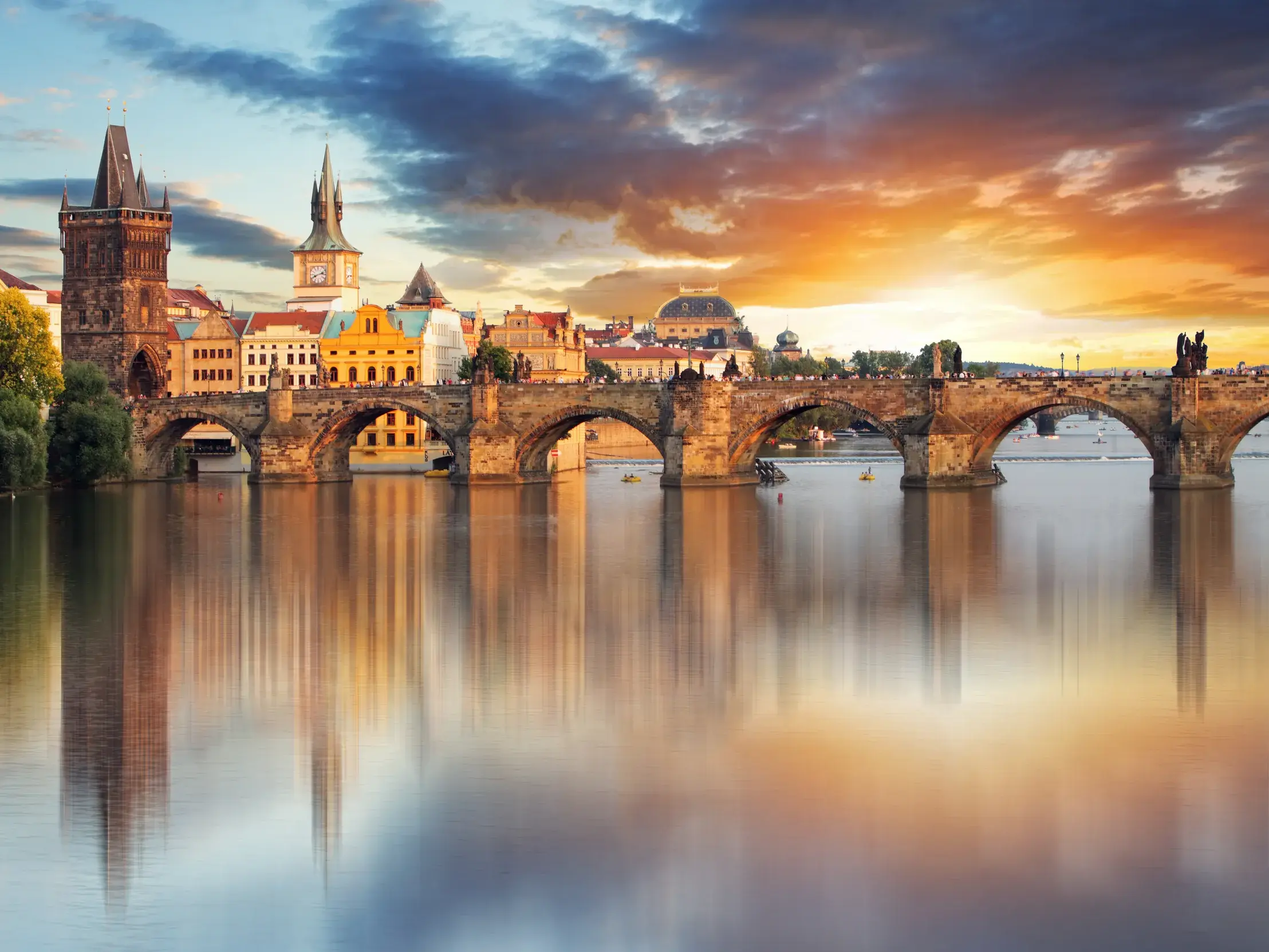 Malerischer Blick auf die historische Karlsbrücke und die Prager Altstadt bei Sonnenuntergang mit Spiegelung in der Moldau.