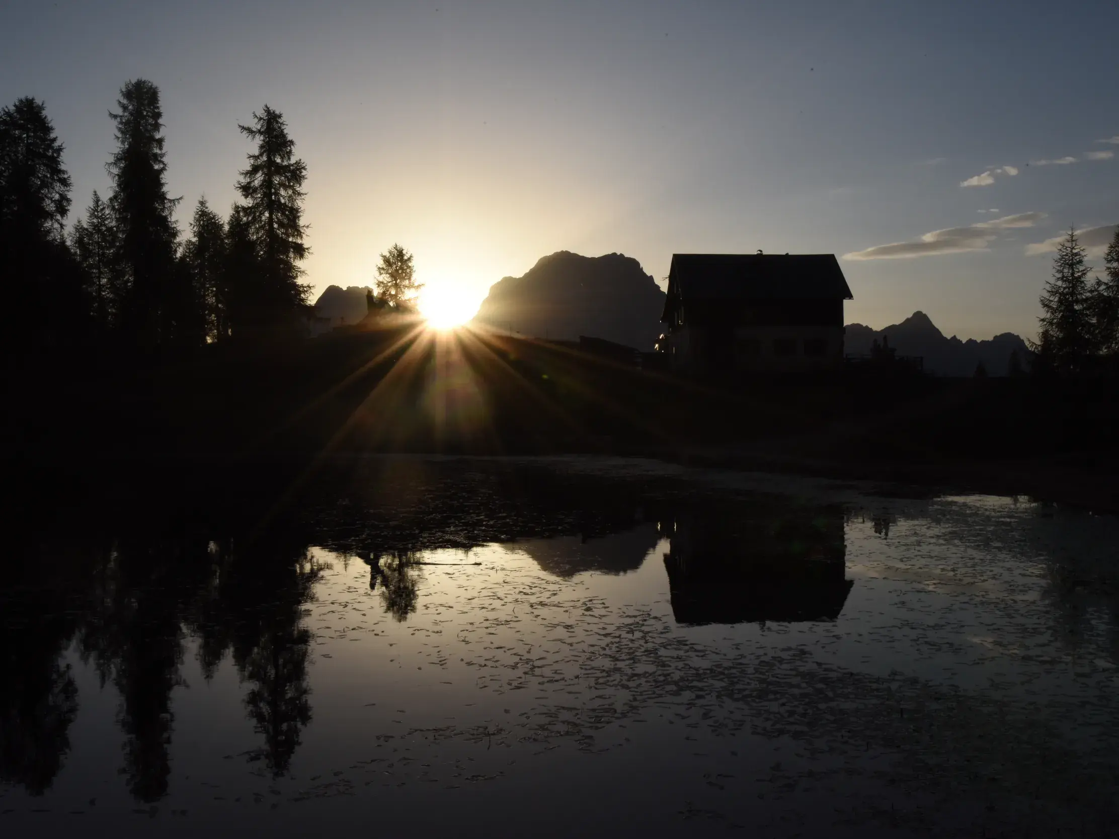 Das idyllische Rifugio Croda da Lago in den Dolomiten spiegelt sich bei Sonnenaufgang im klaren Wasser des Bergsees.