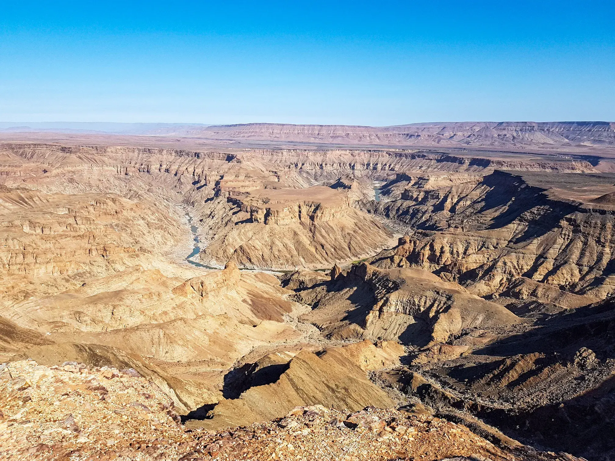 Ausblick von einer Wanderung auf die gewaltige, sonnenbeschienene Felslandschaft des Fish River Canyon in Namibia.