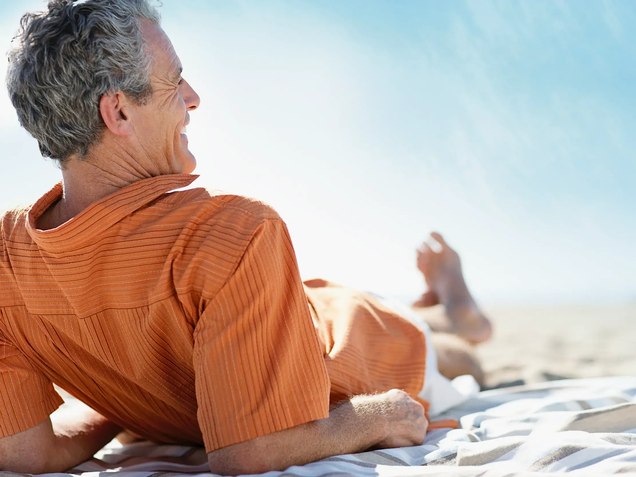 Ein Reiseteilnehmer genießt die freie Zeit bei einer Studienreise und entspannt sich lachend am sonnigen Strand auf Korfu.