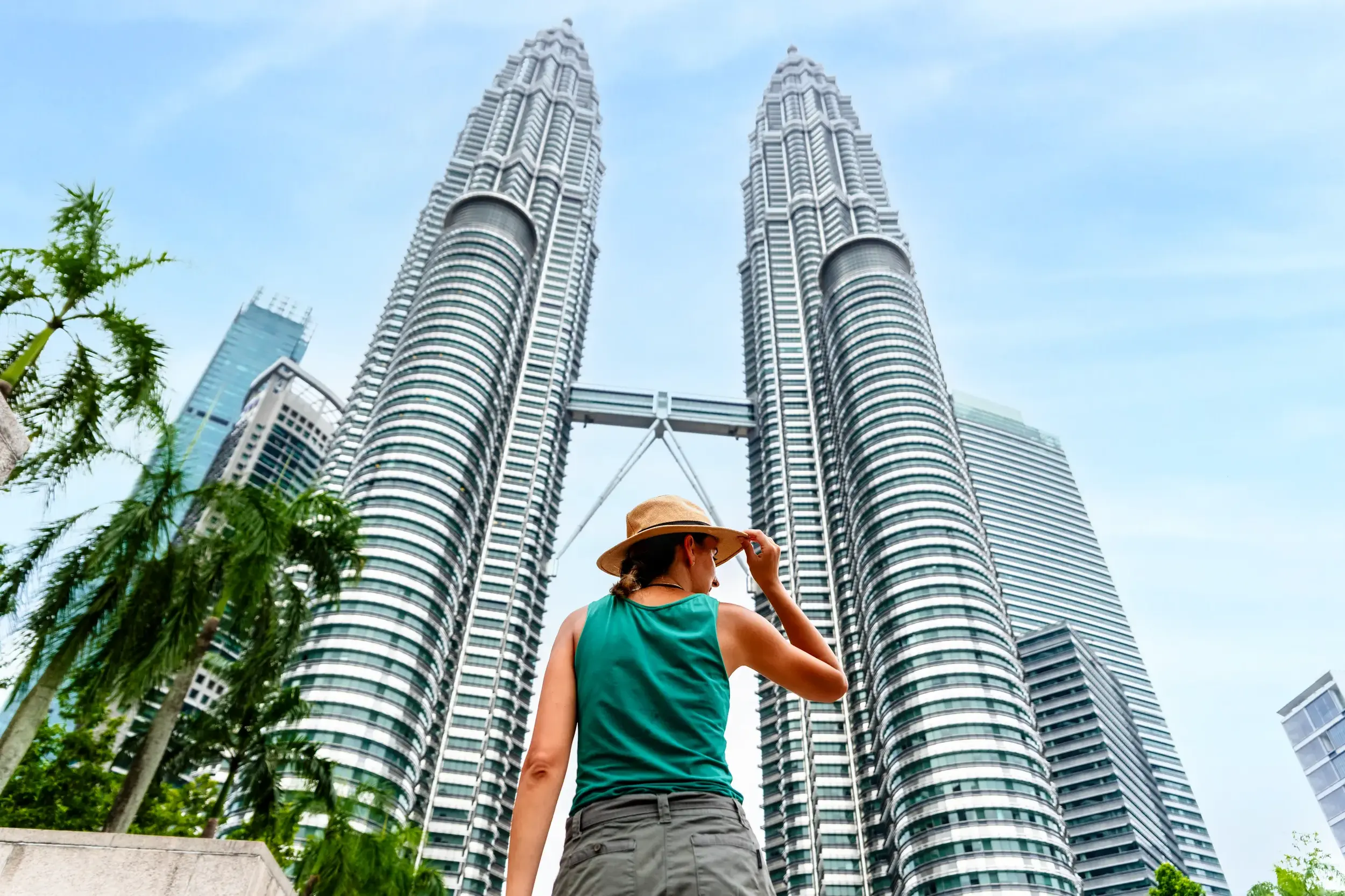 Junge Reisende in Kuala Lumpur bewundert die beeindruckende Architektur der berühmten Petronas Towers aus der Froschperspektive.
