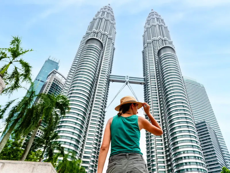 Junge Reisende in Kuala Lumpur bewundert die beeindruckende Architektur der berühmten Petronas Towers aus der Froschperspektive.